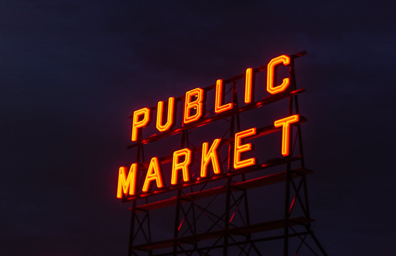 Illuminated Public Market neon sign glowing against a twilight sky.